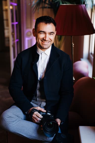 A man with a camera sitting on a couch.